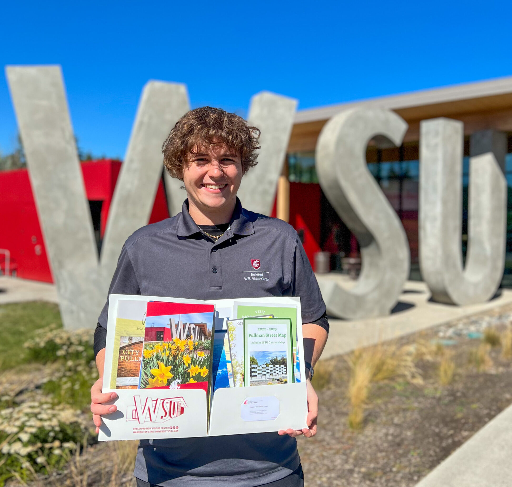 Young man holding a folder full of information available at the WSU Brelsford Visitor Center