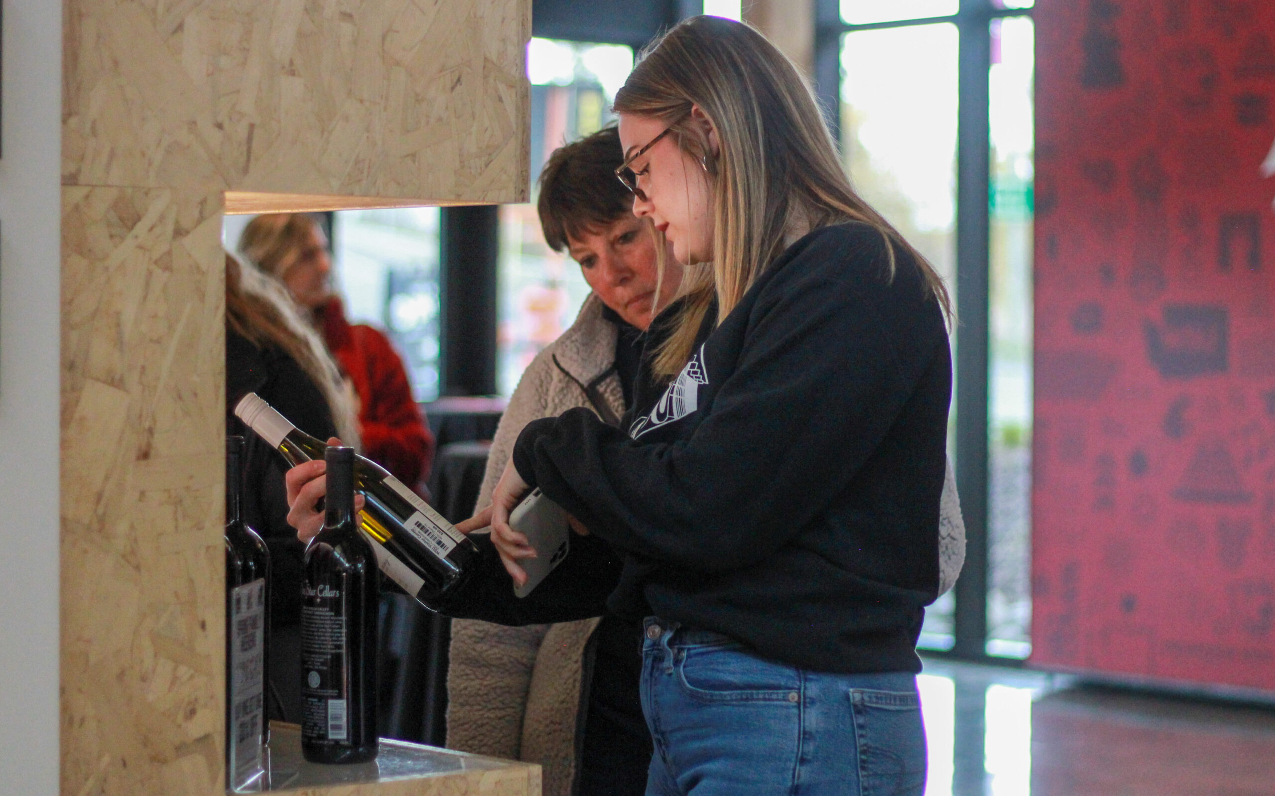 An image of a Brelsford Washington State University Visitor Center employee assisting a visitor with a wine purchase inside the facility.
