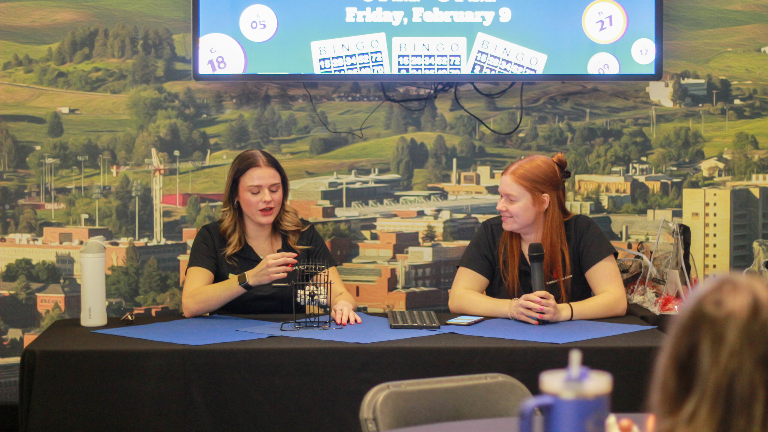 An image of two Brelsford Washington State University Visitor Center employees calling Bingo numbers during an event at the facility.