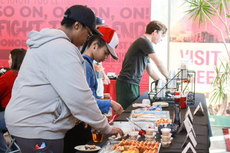 An image of individuals going through a buffet line of food during an event at the Brelsford Washington State University Visitor Center.