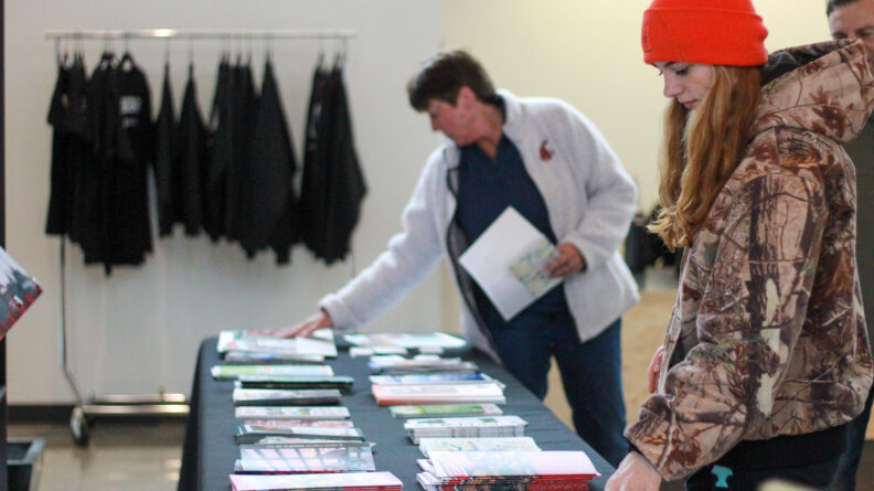 An image of a prospective student and visitor looking through a table of brochures during a Washington State University Pullman admissions event at the Brelsford WSU Visitor Center.