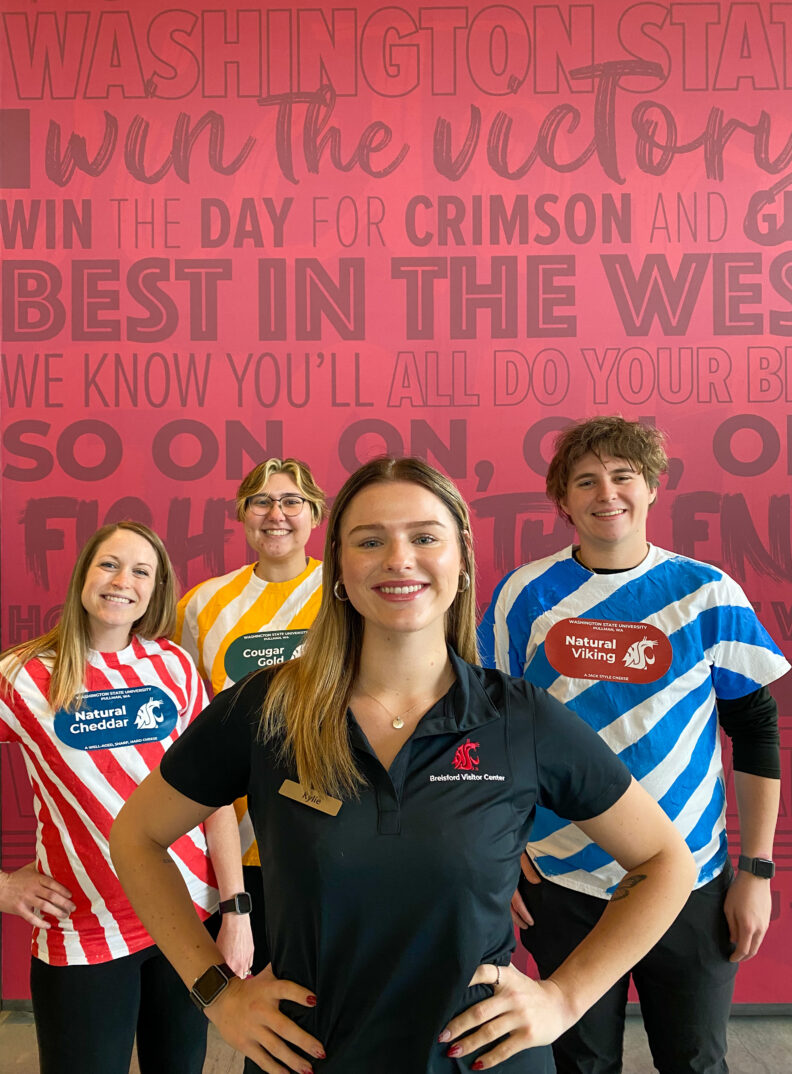 An image of a Brelsford Washington State University Visitor Center employee in the forefront of three others dressed as cans of Cougar Cheese for Halloween.