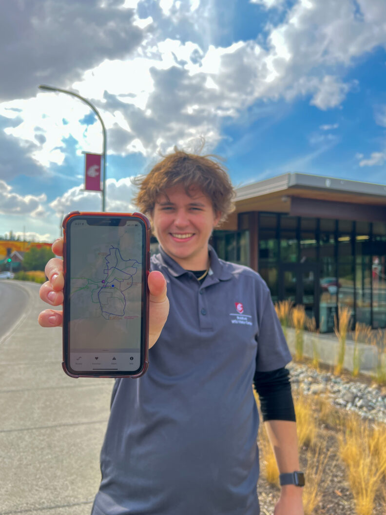 An image of a Brelsford Washington State University Visitor Center employee showing the Pullman Transit app on a mobile device.