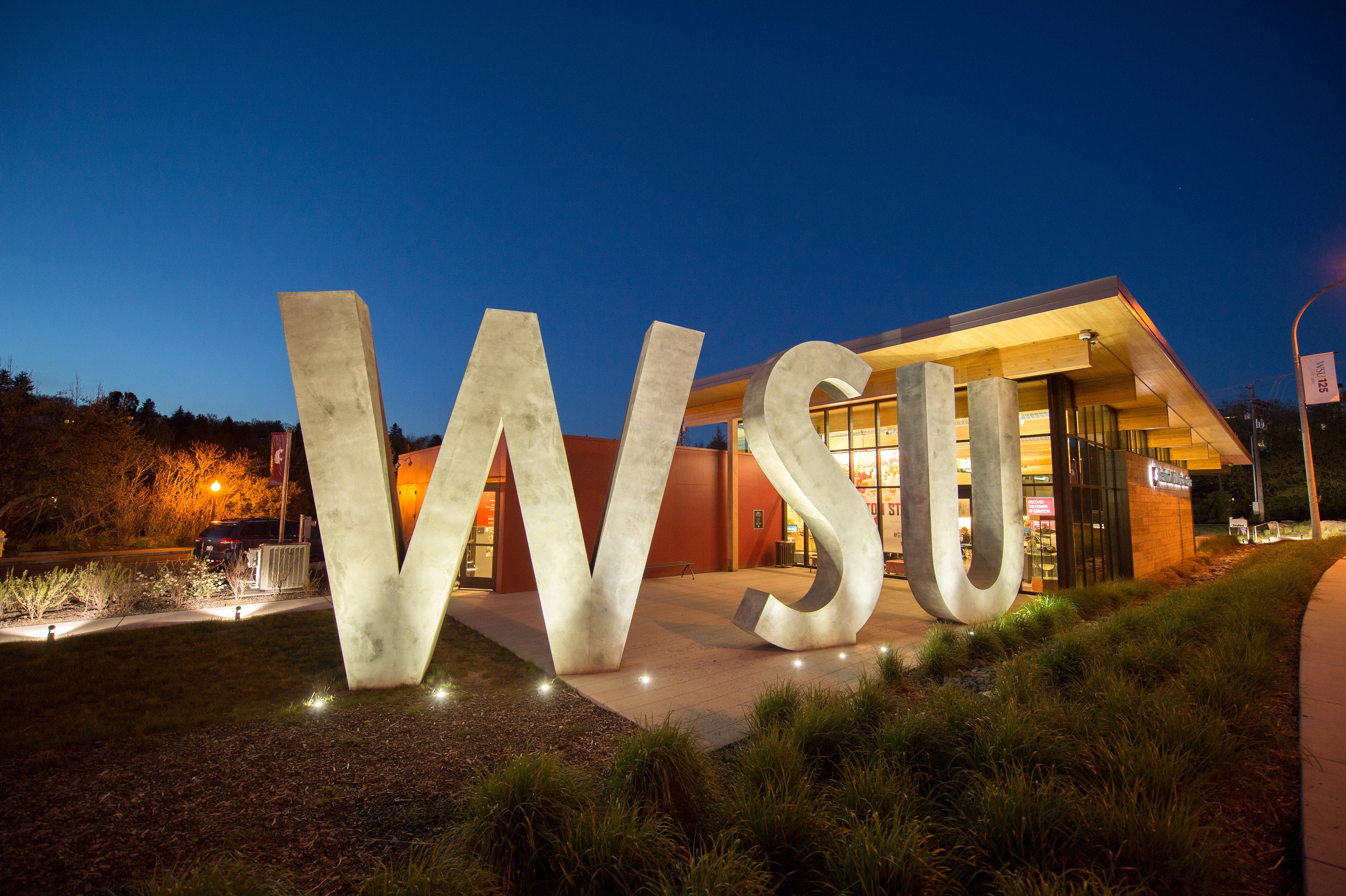 Enormous W-S-U concrete letters in front of the Visitor Center at night.