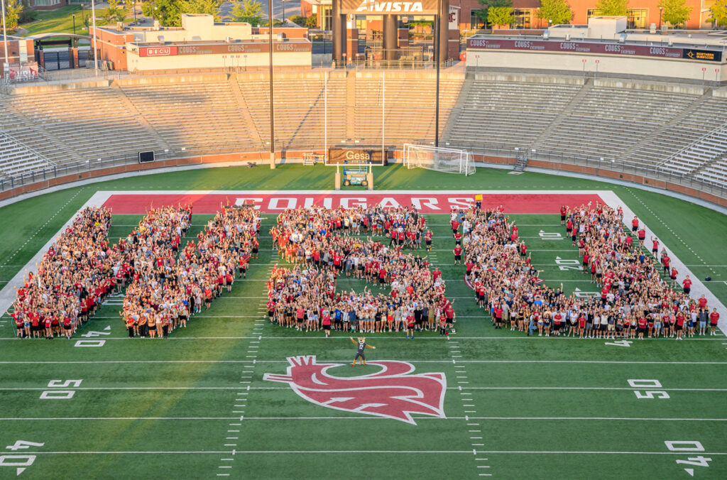 Image of people grouped together to form the letters W-S-U on football field in Pullman, WA