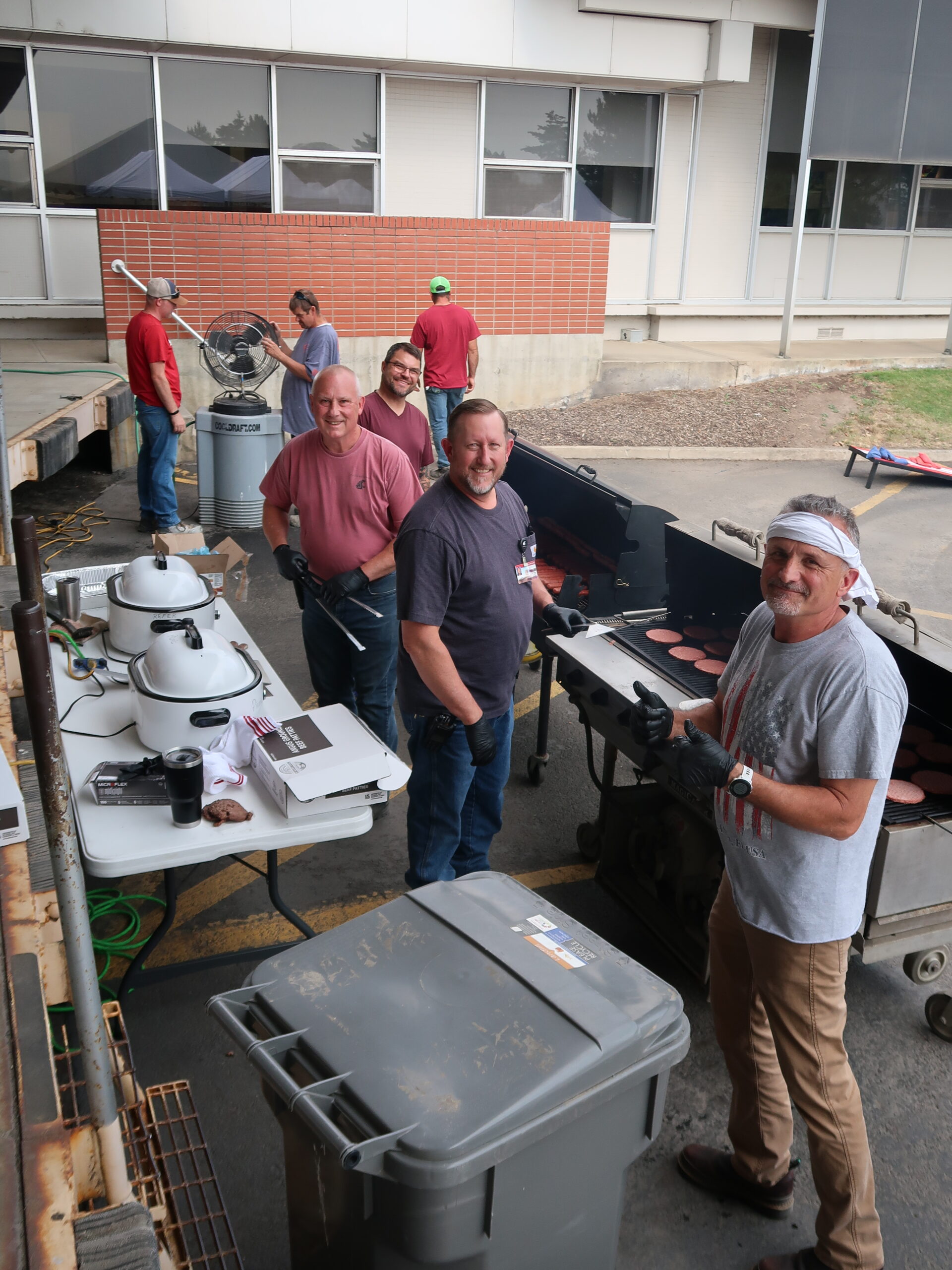 Image of a group of men tending to the outdoor grill at the Facility Operations annual picnic.