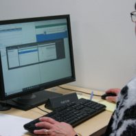 A woman in a black and white sweater stares intently at a computer screen, testing the Workday system for WSU.
