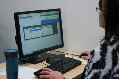 A woman in a black and white sweater stares intently at a computer screen, testing the Workday system for WSU.