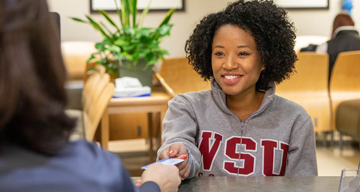 A WSU employee helps a student at a window counseling appointment.