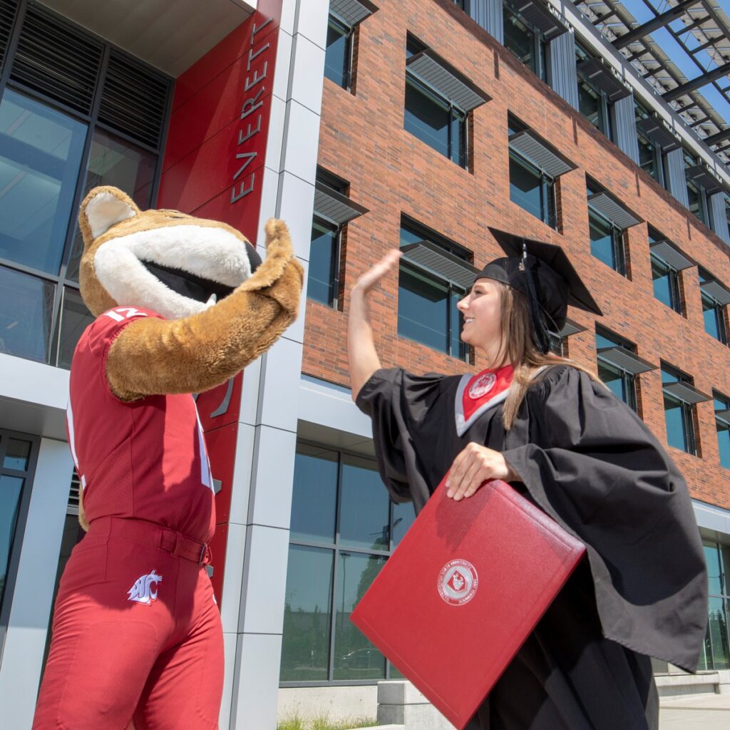 Graduating WSU student high fives mascot Butch T. Cougar.