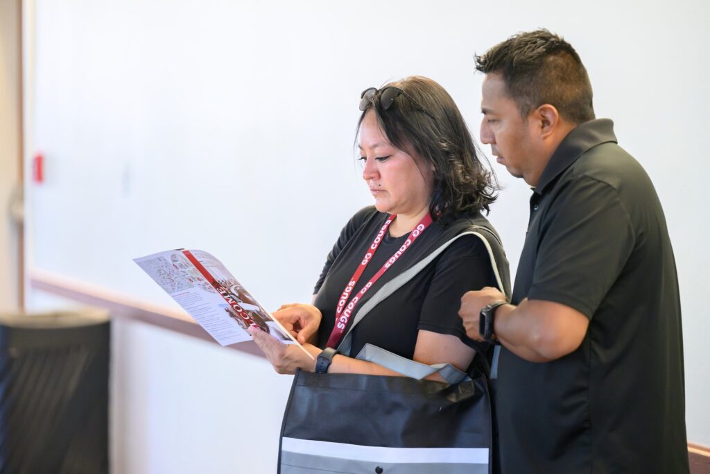 Two parents go look over flyers at new student orientation.