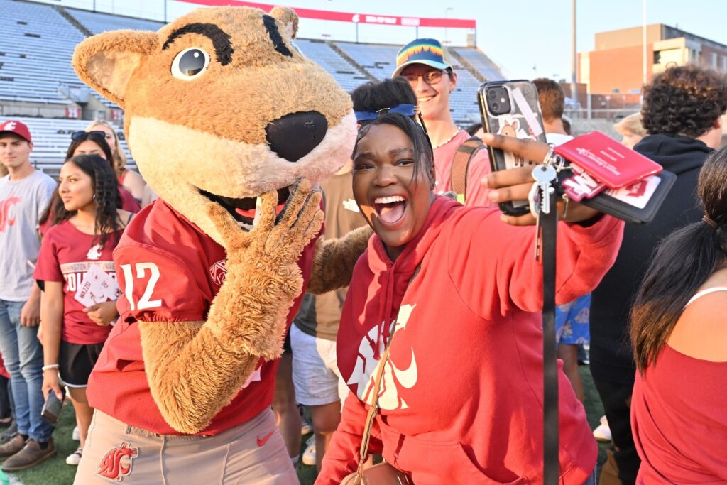 A student poses for a selfie with Butch T. Cougar in Martin Stadium.