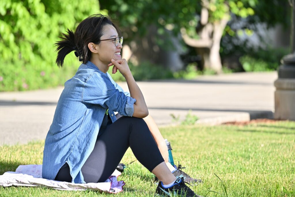 A WSU graduate student listens to music while sitting on the grass outside Bryan Hall.