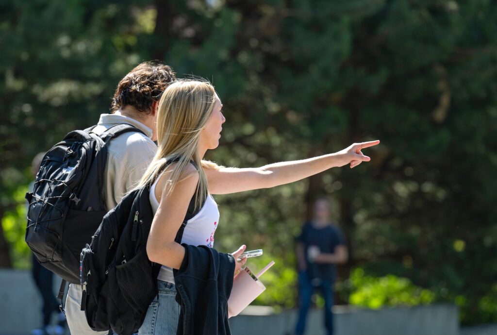 A student outside points towards something on campus.