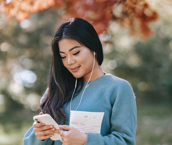 A woman compares a notebook with information on her cell phone.