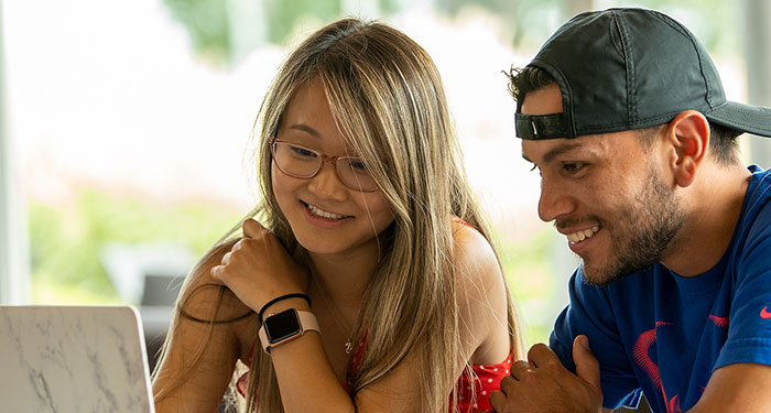 Students working at a shared laptop computer.