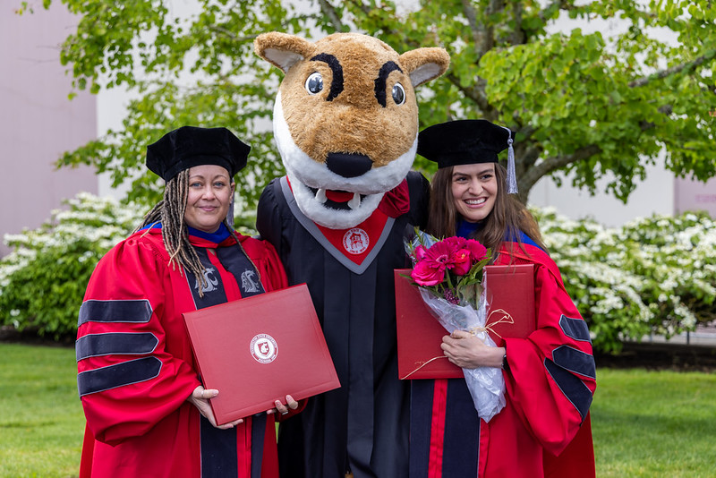 Five WSU students outdoors on campus holding up a cougar head flag.