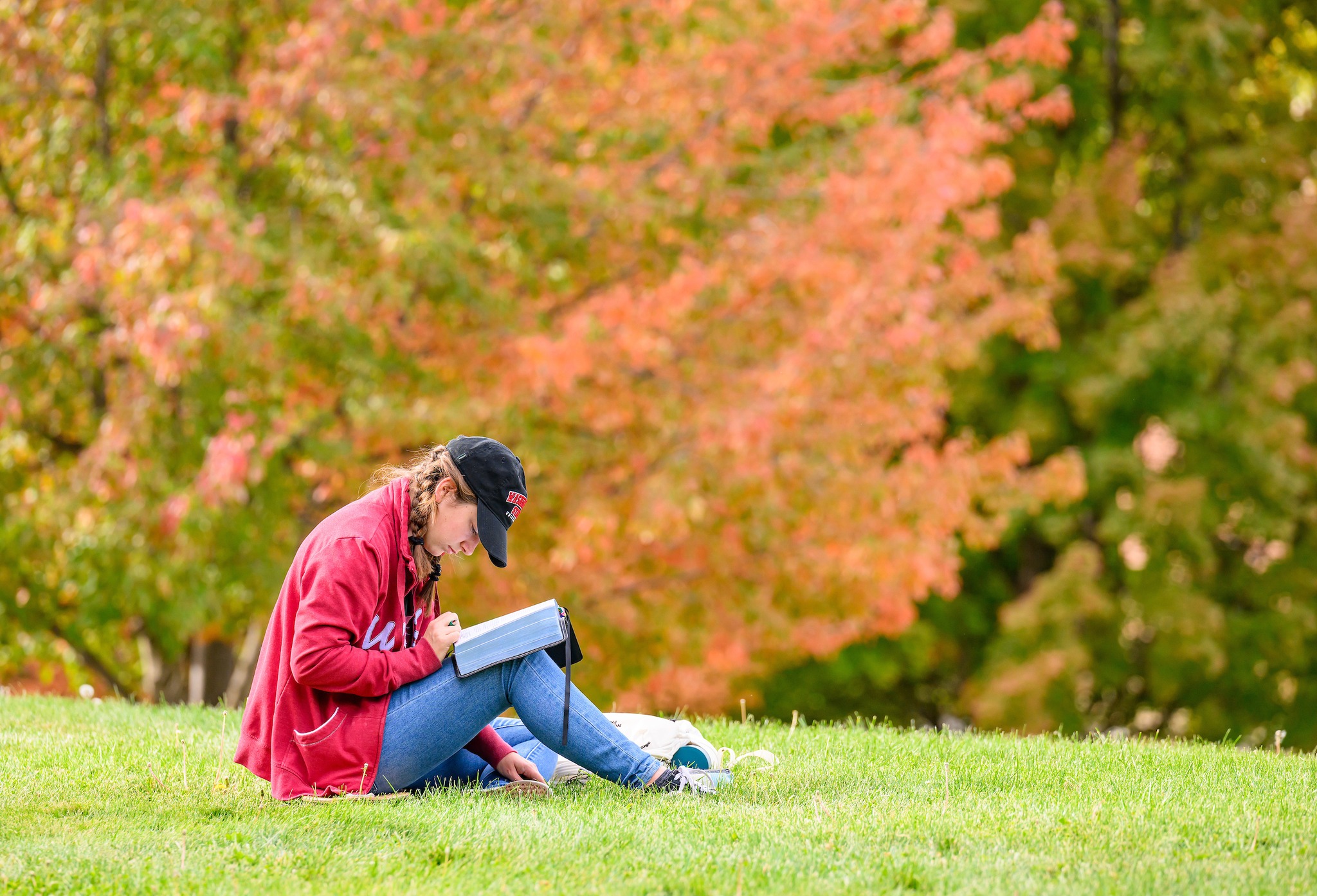 A student studies outside on the grass.