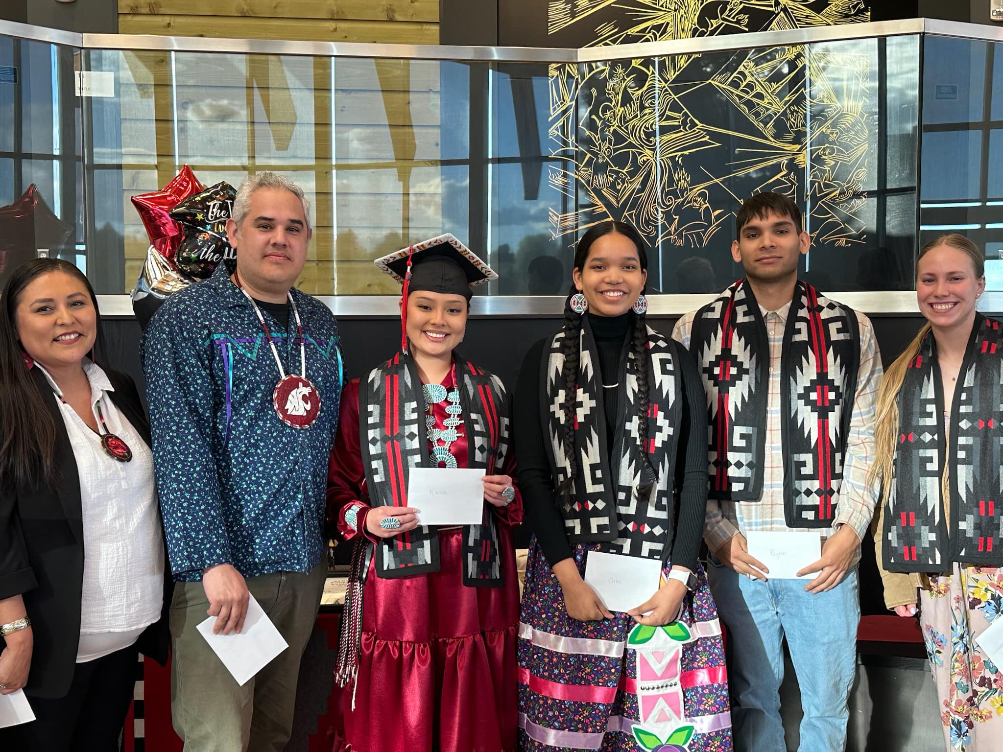 A group of graduating native cougs poses for a photo wearing tribal stoles.