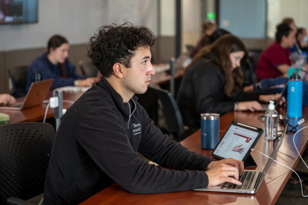 A WSU student sitting in a lecture class and taking notes on their laptop.
