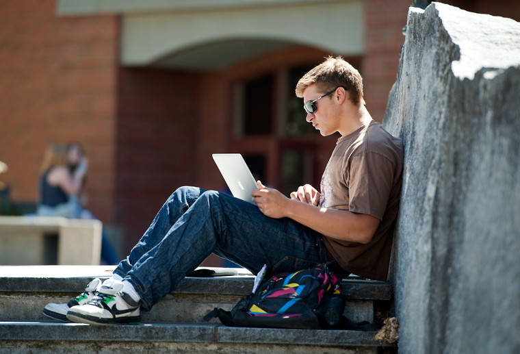 A student reads a book outside the library.