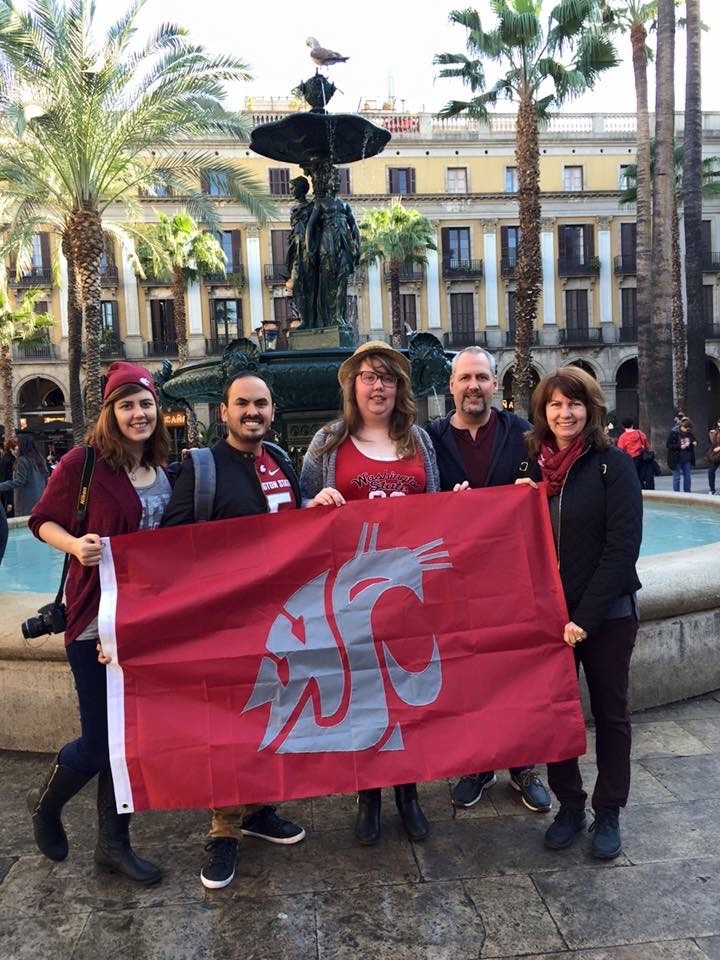 Five members of the Ohl family holding a crimson WSU Coug flag in front of a water fountain.