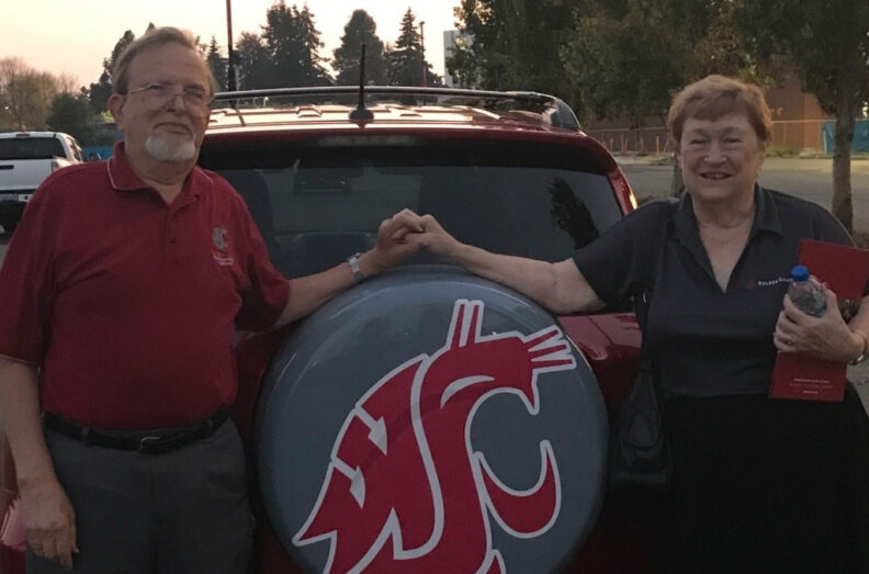 Dick ’64 and Pam ’68 Bagnall holding hands above a spare tire with a WSU logo