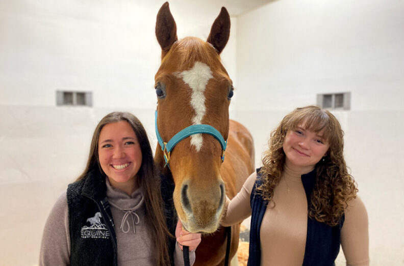 Fourth‑year veterinary student Maddie Gray (left) and third‑year veterinary student Hedy Seeber (right) pose with a horse inside the Veterinary Teaching Hospital on the WSU Pullman campus (photo courtesy of the College of Veterinary Medicine).