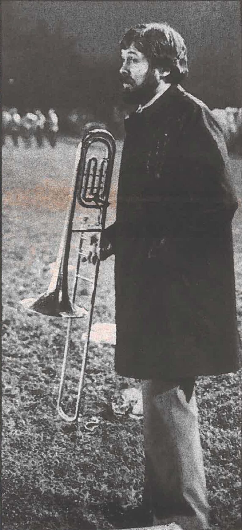 Gary holding a trombone during a band session on the football field at Rogers High School, 1978