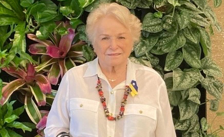 Barbara Stephanus, a longtime supporter of medical research, poses in front of a green plant wall at a WSU philanthropy event.