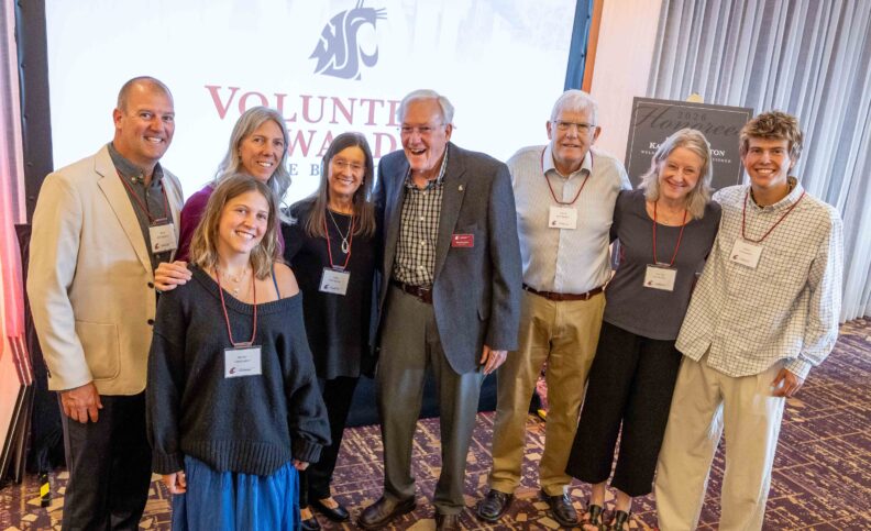 The Hambelton family gathers for a photo in front of the Volunteer Awards Celebration screen, including Gibson Distinguished Volunteer Award recipients Mike and Kathy Hambelton.