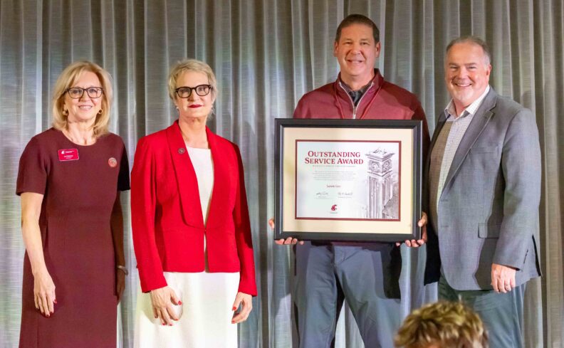 From left, WSU Foundation board director Liz Pritchard, WSU President Betsy Cantwell, honoree Lewis Lee, and WSU Foundation CEO Mike Connell on stage as Lee holds his framed Outstanding Service Award at the 2026 Volunteer Awards Celebration.