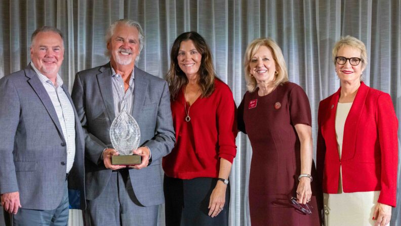 Scott and Lisa Taylor hold their crystal Brotherton Cougar Spirit Award on stage with three WSU Foundation representatives at the 2026 Volunteer Awards Celebration.