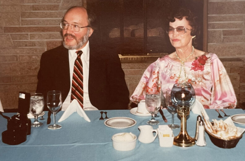 Dr. Roy Filby and another attendee sit together at a banquet table set with glassware and table settings.