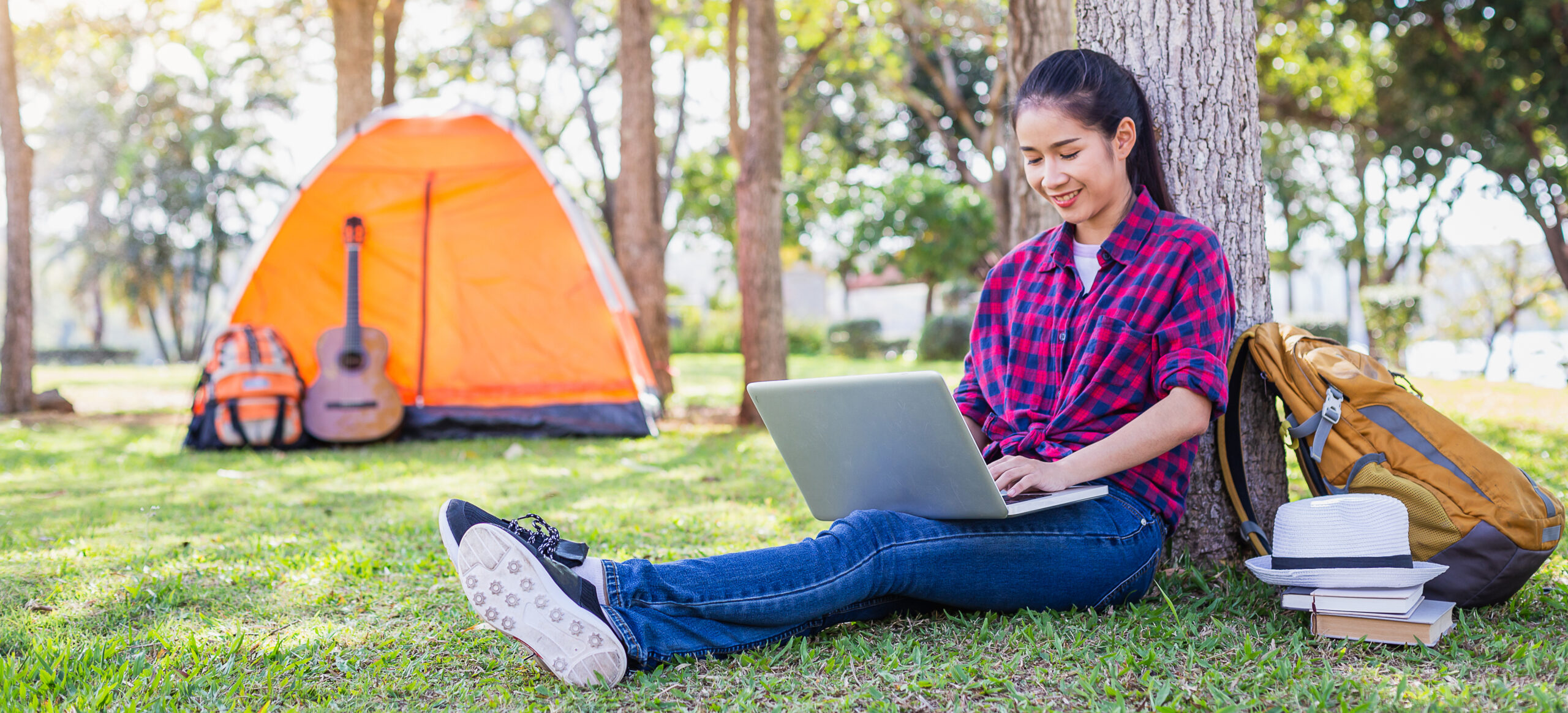 Young Asian woman working with laptop and sitting at outside camping tent, Camping, vacation and travel concept