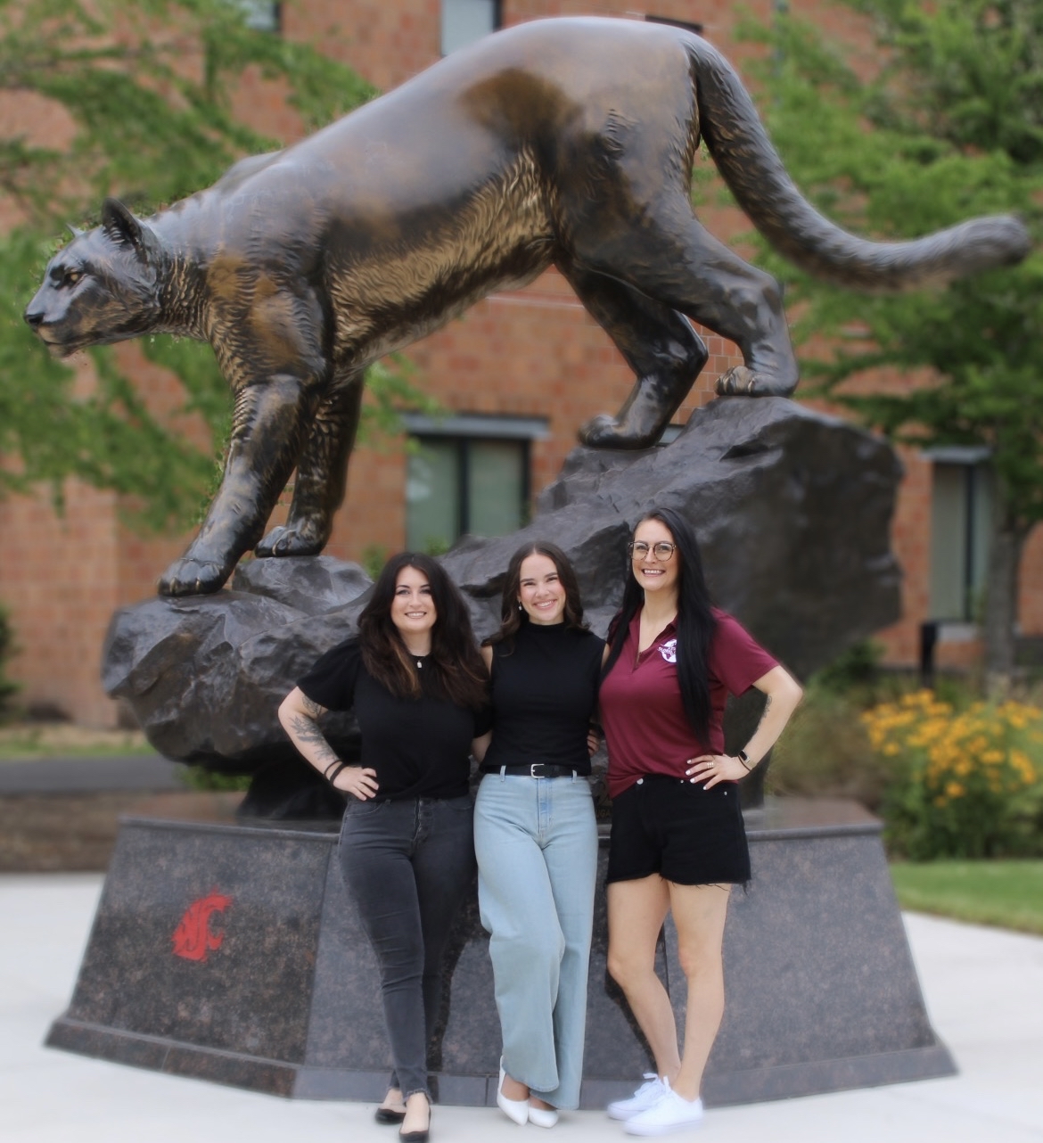 ASWSUG Director of Legislative Affairs Alexiis, President Hannah, and Vice President Rikki posing in front of the Cougar statue on campus.
