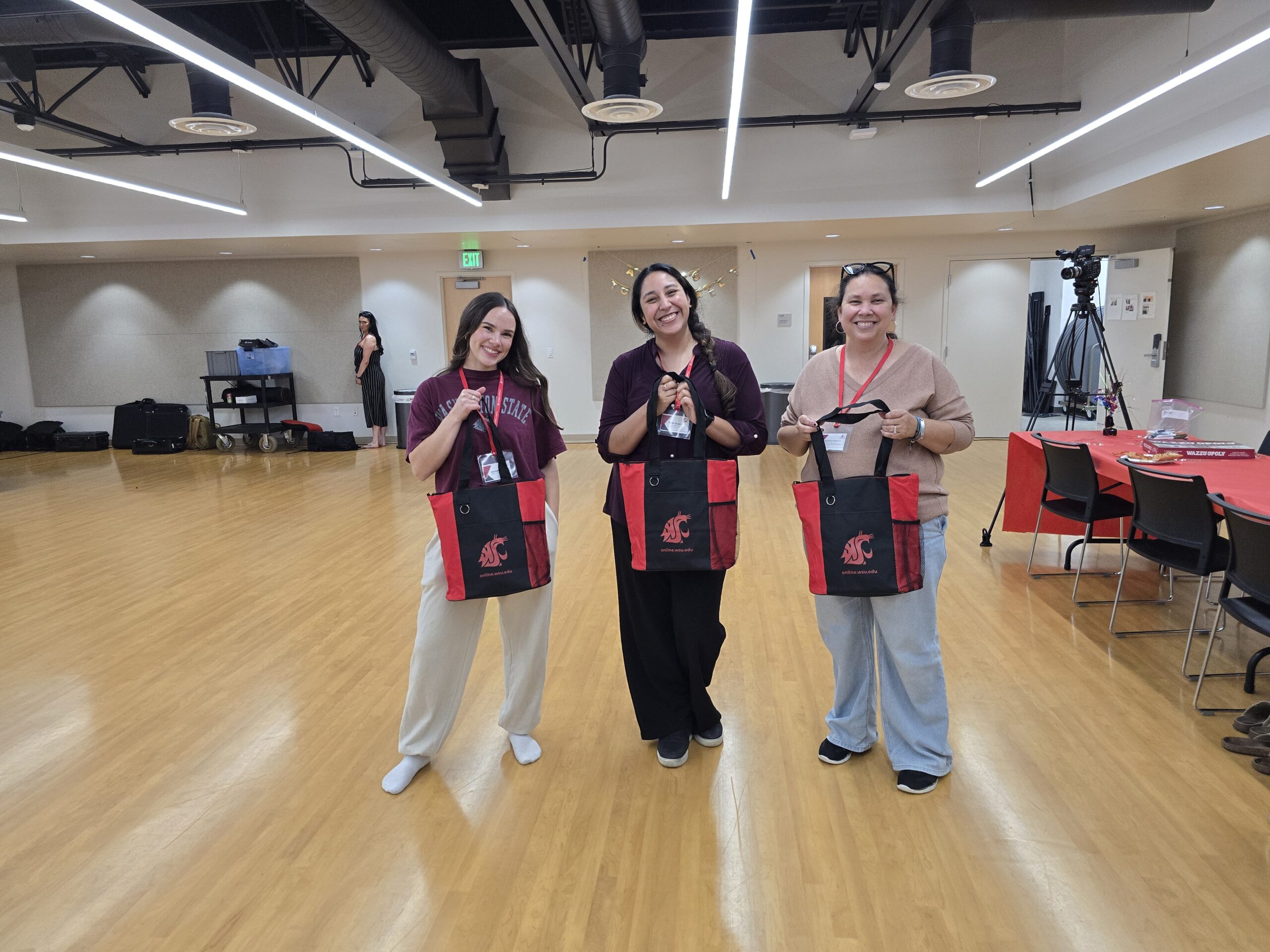 ASWSUG President Hanna, Director of Promotions Sarah, and student Aunjelique holding WSU branded bags and smiling.