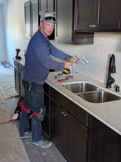 Solomon Jacobs works as an electrician, using a power drill while installing electrical wiring in a kitchen.