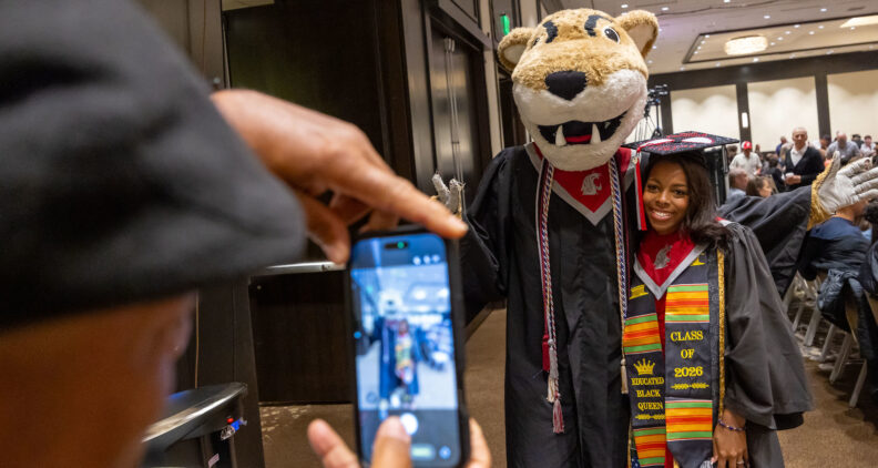 2026 graduate posing for a photo with the WSU Butch mascot.