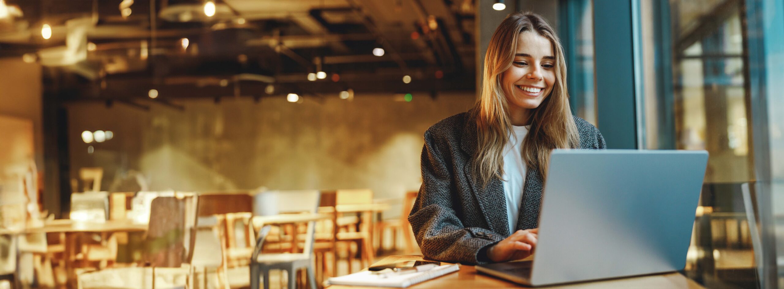 Photo of happy blonde woman on laptop in a cafe
