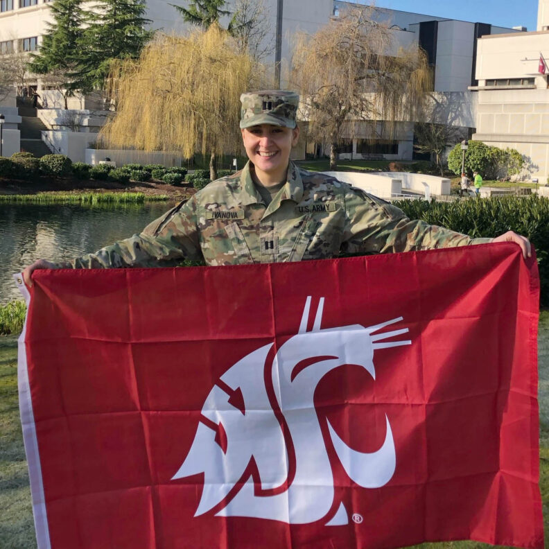 Photo of woman us US Army uniform holding WSU flag.