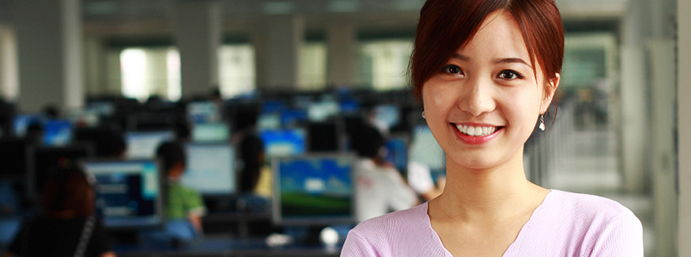 Woman smiles at camera in front of classroom