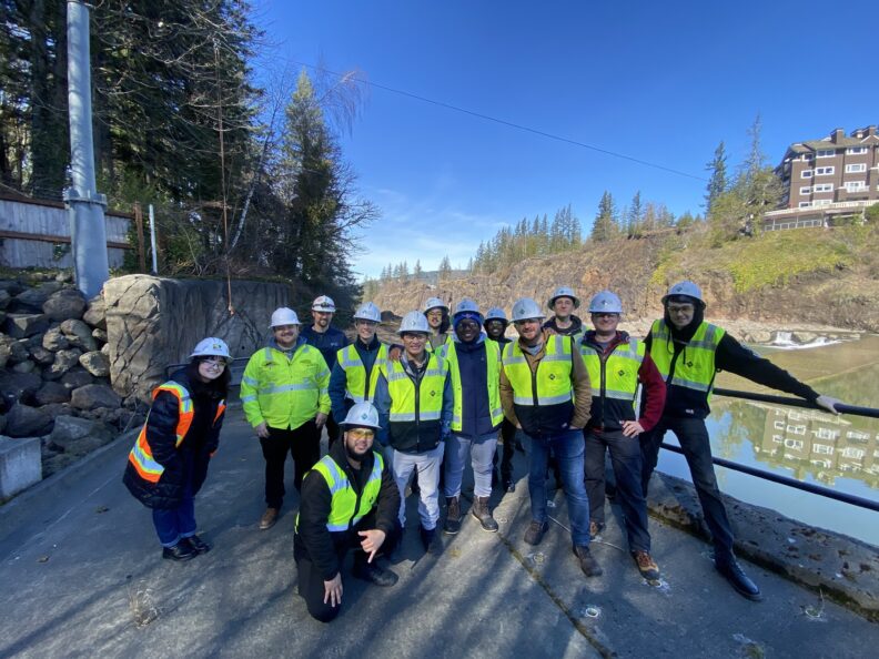 Students in yellow safety vests posing in front of river.