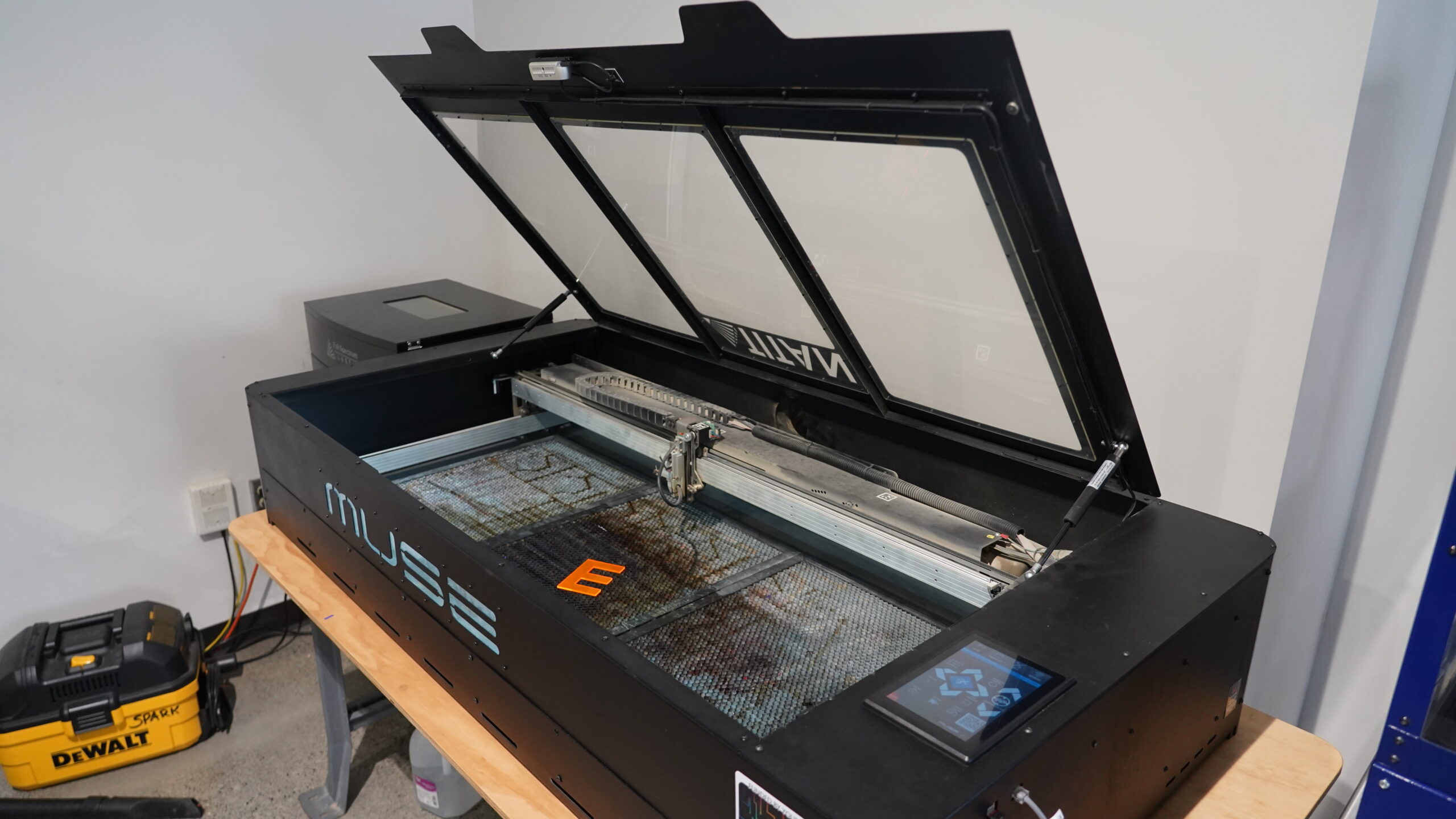 Large laser cutting machine with lid open. Cut material shown inside.