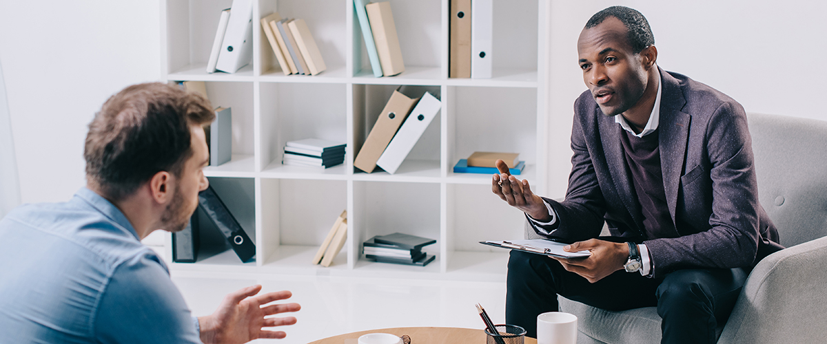 African American psychiatrist talking to young male client