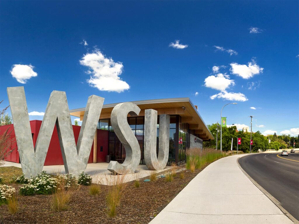 A tall sculpture of the letters W S U next to a glass-walled building.