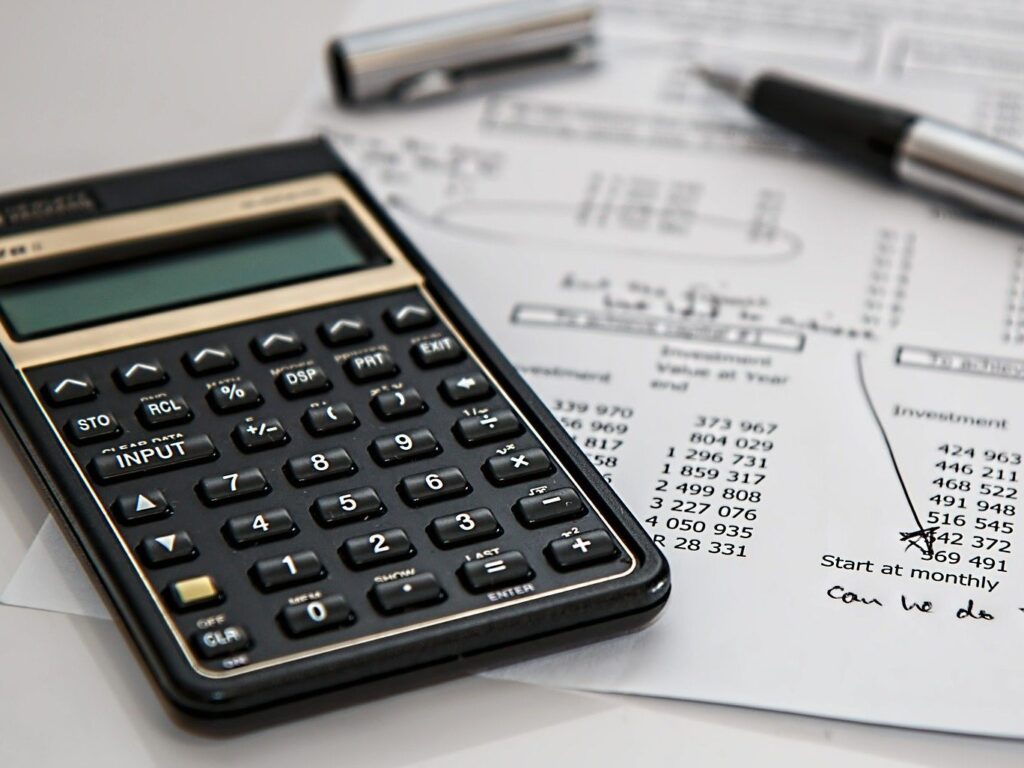 Close up of a calculator sitting on top of a printout of a spreadsheet.