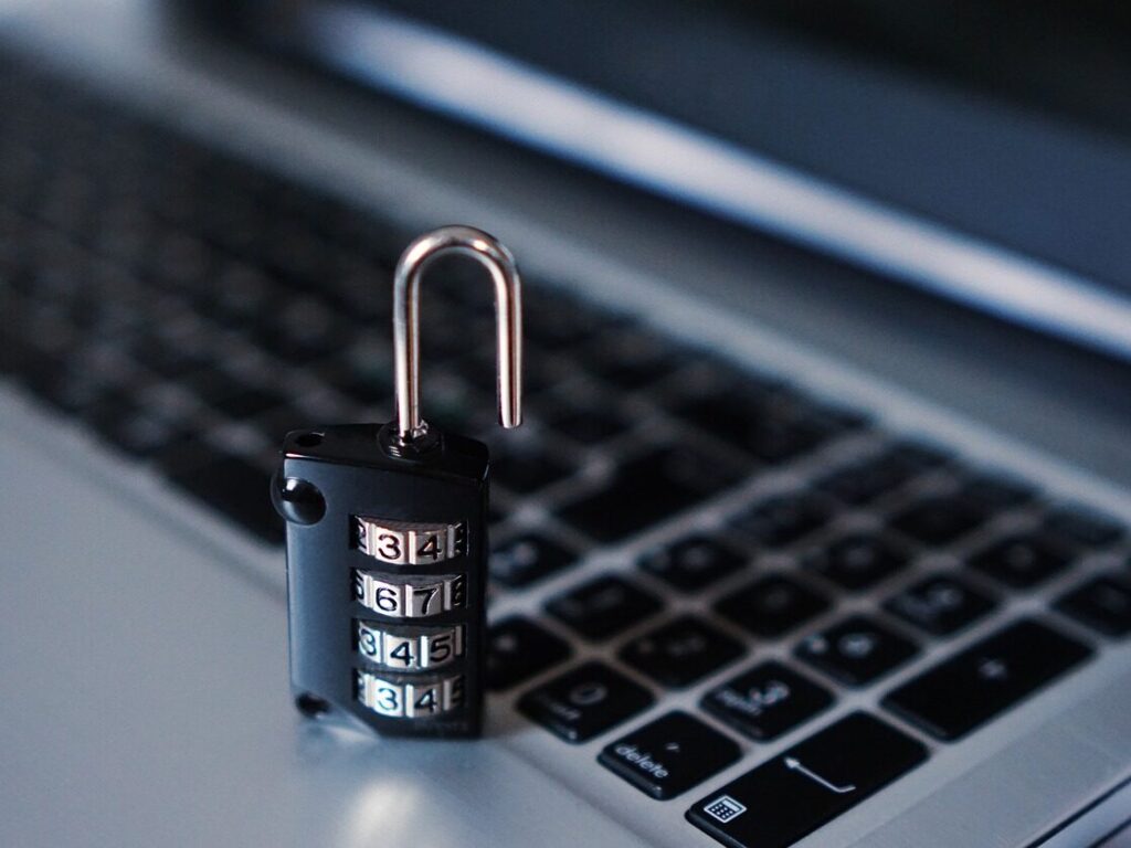 Close-up of a laptop keyboard with an open combination lock on it.