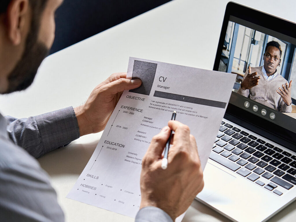 A person looking at a resume and video chatting on a laptop.