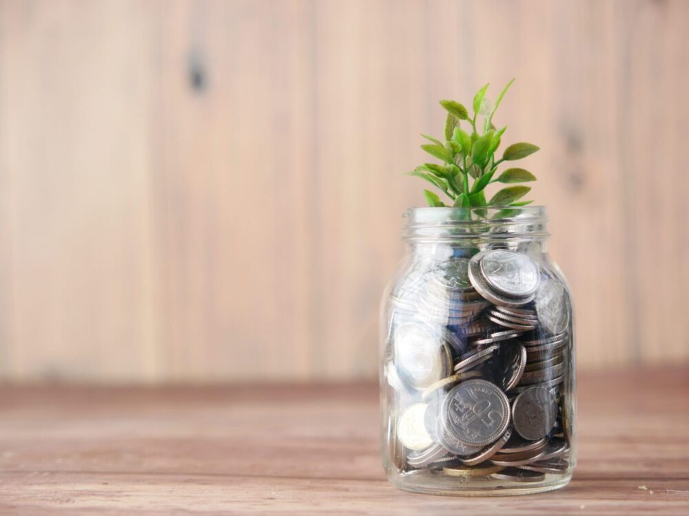 Image of a jar of change with a plant growing out of it.